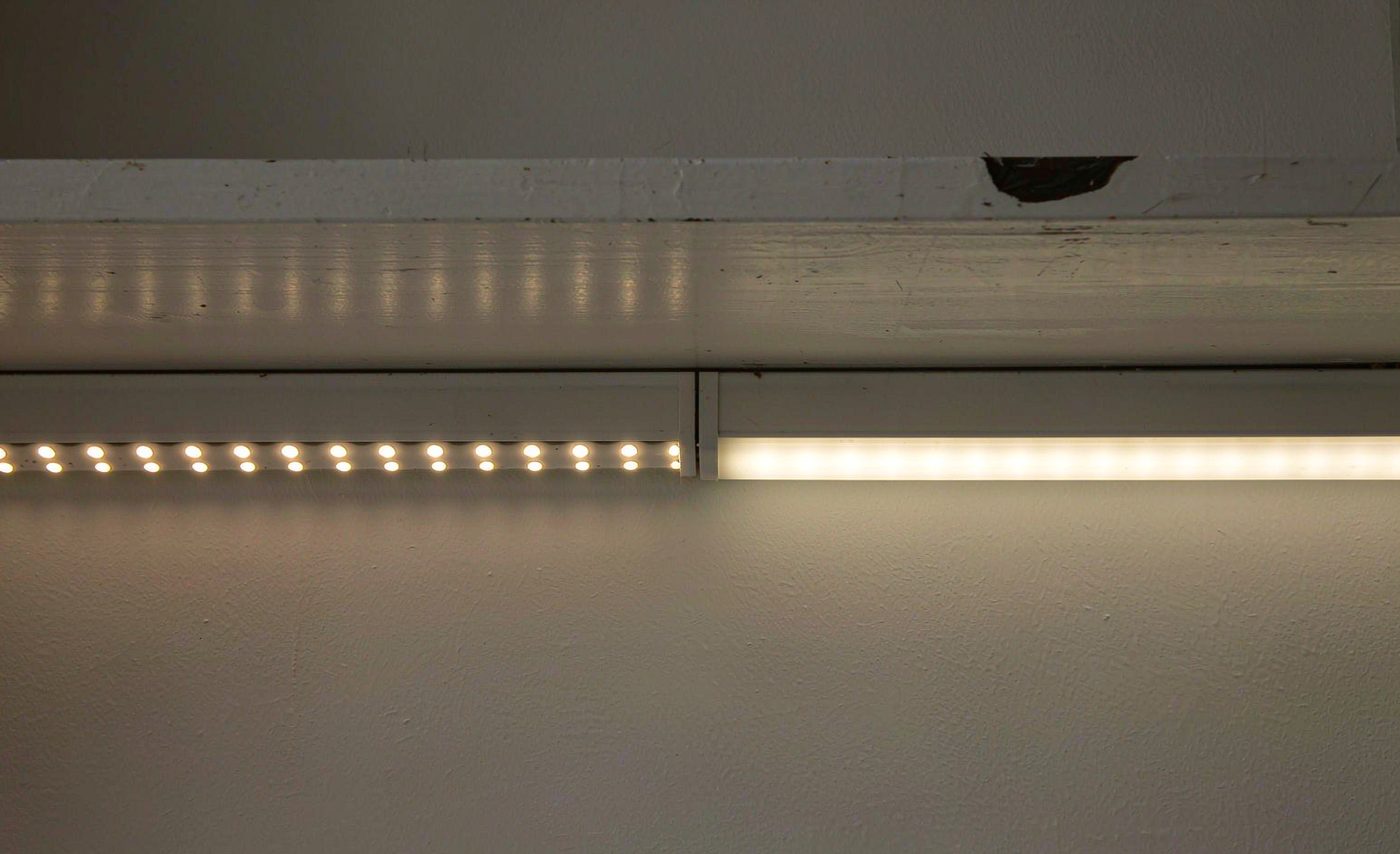 An exposed SMD strip washing a wall with visible dotted scallops on the left, next to a COB strip behind a diffuser producing one continuous even band of light on the right